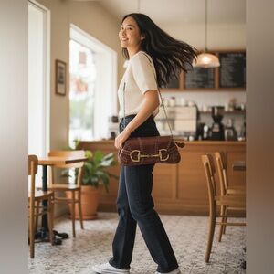 Rina Rich faux leather baguette shoulder bag featuring a gold horse bit